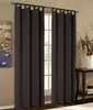 A pair of dark brown tab-top curtains hangs in front of a window, with a painting on the left and a side table with decorative items on the right. Produktbild-Vorschau