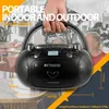 A person holds a portable boombox in a setting that appears to be a home or outdoor gathering. Produktbild-Vorschau