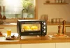 A mini oven in a kitchen setting, with food inside and on the counter. Náhľad obrázku produktu