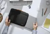 A person is placing a laptop into a laptop bag on a desk. Náhľad obrázku produktu