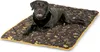 A black dog lying on a brown dog mat with paw print and bone patterns. Náhled obrázku produktu