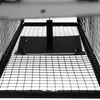A close-up, low-angle view of the interior of a metal cage trap, showing the wire mesh floor and a central metal plate with a vertical support. Voir les images du produit