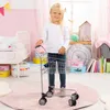 A young girl stands in a bedroom holding a toy shopping cart. Produktbild-Vorschau
