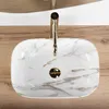A top-down view of a marble-patterned sink with a gold faucet, placed on a wooden surface. Anteprima dell’immagine prodotto