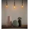 Three pendant lights hang above a display of three decorative vases on a wooden tray. Voir les images du produit