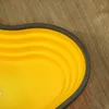 A close-up view of a yellow, heart-shaped, collapsible basin with a gray rim, resting on a wooden surface. Náhľad obrázku produktu