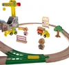 A wooden train set with various accessories like a crane, trucks, figures, and buildings, arranged on a track. Podgląd zdjęcia produktu