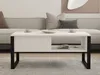 A white coffee table with black legs is placed in a living room setting, in front of a sofa. Produktbild-Vorschau