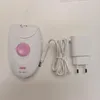 A white Braun Silk Epil 1 epilator with a pink dial and a white charging cable and adapter are laid out on a white surface. Produktbild-Vorschau