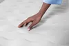 A hand touching a white mattress. Produktbild-Vorschau