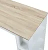 A close-up view of the top surface and side of a white and wood-effect bar table with shelves. Náhled obrázku produktu