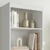 A close-up view of a white bookshelf with books and decorative vases. Produktbild-Vorschau