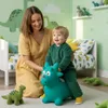 A mother and child playing with a green inflatable dinosaur toy in a child's room decorated with dinosaur themes. Podgląd zdjęcia produktu