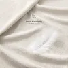 A close-up of a soft, textured fabric, possibly a blanket or bedsheet, with a single white feather resting on it. Text overlays indicate the product's softness and coziness. Produktbild-Vorschau