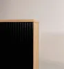 A close-up view of the corner of a cabinet with a fluted black front and a wooden top. Náhled obrázku produktu