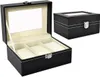 A black watch organizer box with a clear lid is shown open, revealing three compartments. Another closed box is visible in the background. Náhľad obrázku produktu
