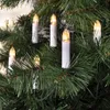 Close-up of white candle-shaped LED lights on a green Christmas tree. Produktbild-Vorschau