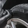 A gloved hand is using a brush to apply product to a car tire. Anteprima dell’immagine prodotto