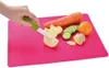 A hand is shown chopping vegetables and fruit on a pink cutting board. Ingredients include a carrot, cucumber, orange, apple, and ginger. Produktbild-Vorschau