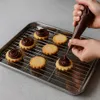 A person is decorating cookies with chocolate frosting on a baking sheet with a cooling rack. Anteprima dell’immagine prodotto