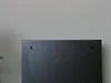 The back of a black cabinet is shown against a light gray wall. Voir les images du produit
