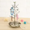 A jewelry tree stand with various bracelets and necklaces displayed on it, placed on a wooden surface with decorative balls in the background. Podgląd zdjęcia produktu