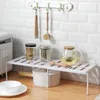 A kitchen shelf organizer with kitchen items on it, placed on a countertop against a tiled wall. Podgląd zdjęcia produktu