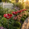 Reihe von roten Solar-Gartenstäben in Mohnblumenform entlang eines Gartenwegs, umgeben von üppigem Grün und verschiedenen Blumen Produktbild-Vorschau