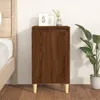 A brown wooden nightstand with three legs is placed next to a bed. There are two framed pictures and a vase with a plant on top of the nightstand. A large potted plant is to the right of the nightstand. Náhled obrázku produktu