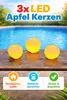 Three apple-shaped LED candles floating in a swimming pool. Produktbild-Vorschau