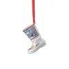 A white ceramic Christmas boot ornament with a winter scene depicted on it, hanging from a red ribbon. Produktbild-Vorschau