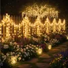 A garden path lined with flowers and illuminated by string lights and lanterns. Anteprima dell’immagine prodotto
