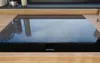 A close-up shot of a black induction cooktop with four heating zones, set into a wooden countertop. Produktbild-Vorschau