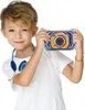 A young boy is holding a colorful digital camera and wearing headphones around his neck. Podgląd zdjęcia produktu