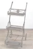 A gray metal plant stand with three shelves and wheels. Produktbild-Vorschau