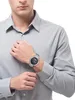 A man wearing a grey shirt and a silver watch on his left wrist. Produktbild-Vorschau