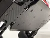A close-up view of the underside of a remote-controlled vehicle, showing the carbon fiber chassis and screws. Voir les images du produit