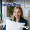 A woman is holding a white pillow in a living room setting. Produktbild-Vorschau