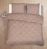A top-down view of a taupe colored comforter and two pillows on a bed, set against a wooden floor. Produktbild-Vorschau