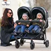 A woman with two babies in a double stroller outdoors. Produktbild-Vorschau