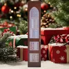 A decorative advent calendar shaped like a bookshelf, set against a festive Christmas background with gifts and a decorated tree. Náhled obrázku produktu