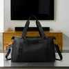 A black duffel bag is placed on a glass table in front of a wooden cabinet and a television. Voir les images du produit
