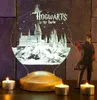A Harry Potter-themed 3D LED lamp with Hogwarts castle design, a Harry Potter figurine, and two lit tea candles on a wooden surface in front of a stone wall. Produktbild-Vorschau