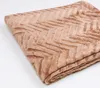 A folded brown blanket with a chevron pattern on a white background. Podgląd zdjęcia produktu