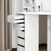 A close-up view of a white vanity table with several drawers open, revealing storage compartments. The background includes a curtain and a shelf with decorative items and cosmetics. Produktbild-Vorschau