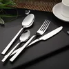 A set of four stainless steel cutlery pieces arranged on a dark surface, with some greenery and ice cubes in the background. Produktbild-Vorschau