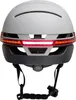 The back view of a white and gray bicycle helmet with integrated red and orange LED lights. Náhled obrázku produktu