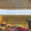 A relaxed outdoor setting with drinks and a hat on a chair, under a bamboo canopy. Produktbild-Vorschau