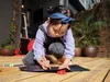 A young girl is drawing on a black paper with crayons on a wooden deck. Anteprima dell’immagine prodotto