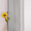 A close-up of a sheer gray curtain with sunflowers in a vase behind it. Produktbild-Vorschau